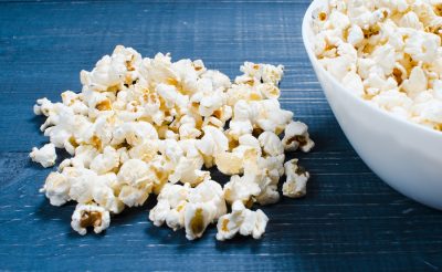 Salty Popcorn Lies On A Wooden Background. The Concept Of Cinema